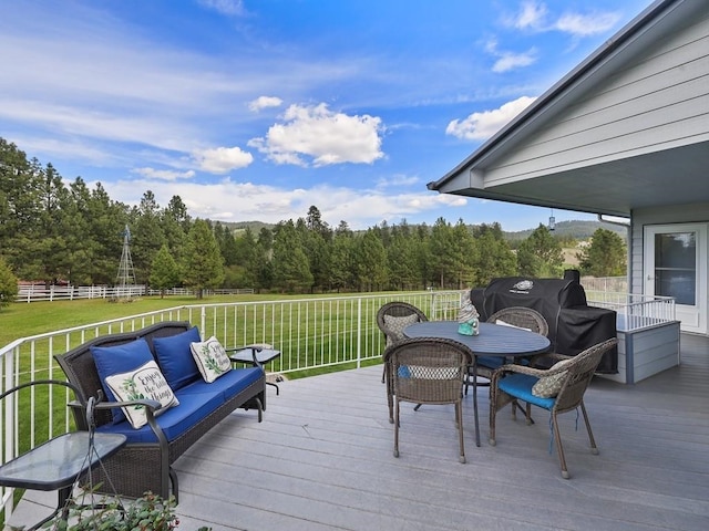 wooden deck featuring a lawn, a view of trees, fence, and outdoor dining space