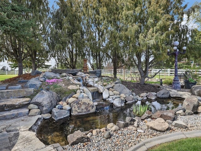 view of yard featuring fence and a small pond