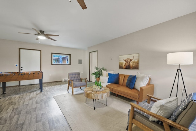 living room featuring baseboards, a ceiling fan, and light wood-style flooring