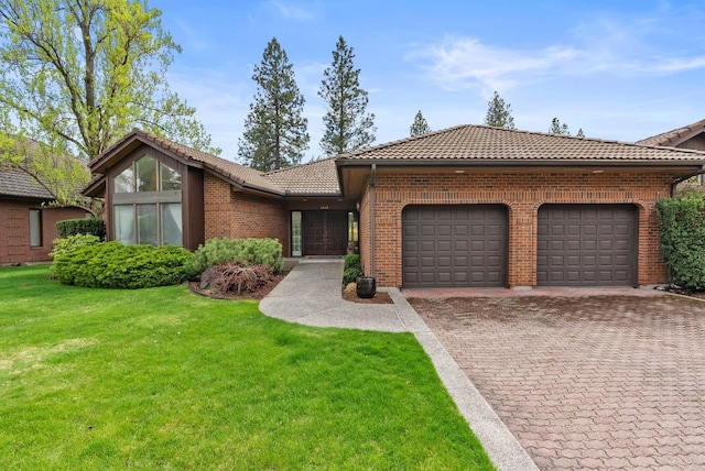 view of front facade with a front lawn, a tile roof, a garage, brick siding, and driveway