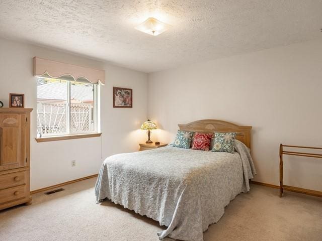 8409 N Pine Meadows Ln, Nine Mile Falls, WA 99026 - bedroom featuring baseboards, visible vents, a textured ceiling, and light colored carpet