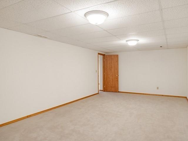 8409 N Pine Meadows Ln, Nine Mile Falls, WA 99026 - spare room with baseboards, light colored carpet, and a paneled ceiling