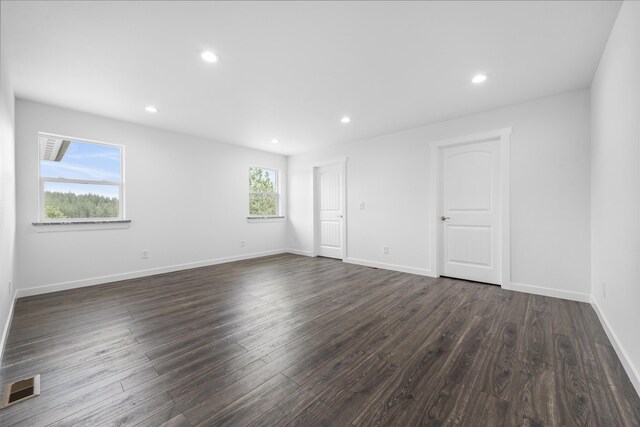 empty room featuring recessed lighting, baseboards, dark wood-style floors, and visible vents