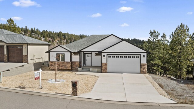 view of front of home with an attached garage, concrete driveway, and stone siding
