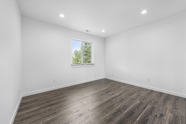 empty room featuring dark wood-type flooring, recessed lighting, baseboards, and visible vents