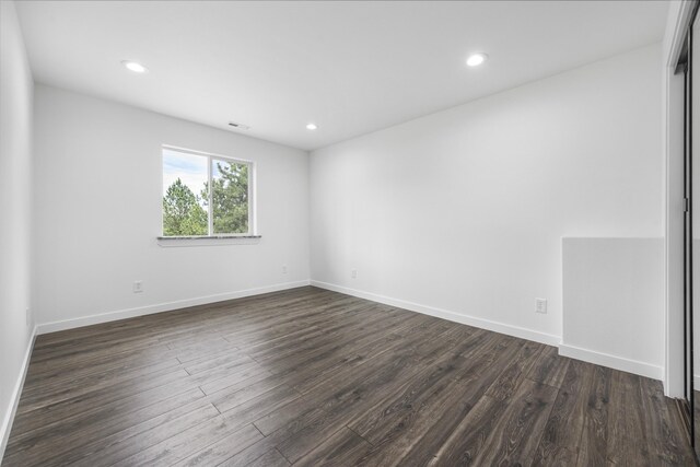 empty room featuring recessed lighting, baseboards, and dark wood-style flooring