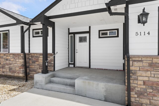 property entrance with a porch and stone siding