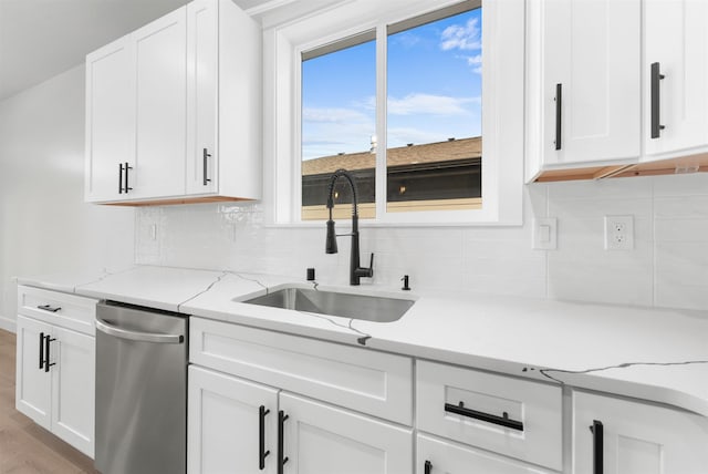 kitchen featuring a sink, tasteful backsplash, stainless steel dishwasher, and white cabinetry
