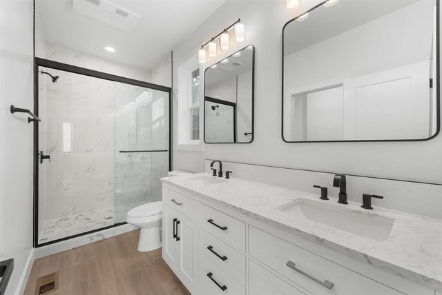bathroom with toilet, a marble finish shower, a sink, and wood finished floors