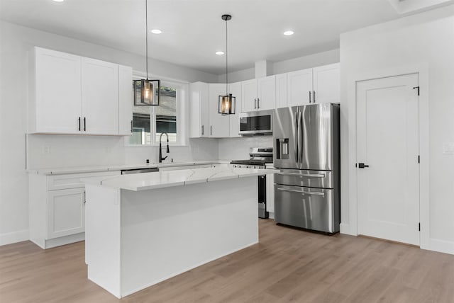 kitchen with appliances with stainless steel finishes, light wood-type flooring, and white cabinetry