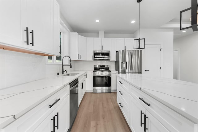 kitchen with backsplash, appliances with stainless steel finishes, light wood-type flooring, a sink, and recessed lighting