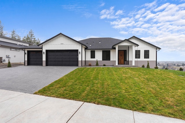 view of front of house featuring board and batten siding, an attached garage, decorative driveway, and a front yard
