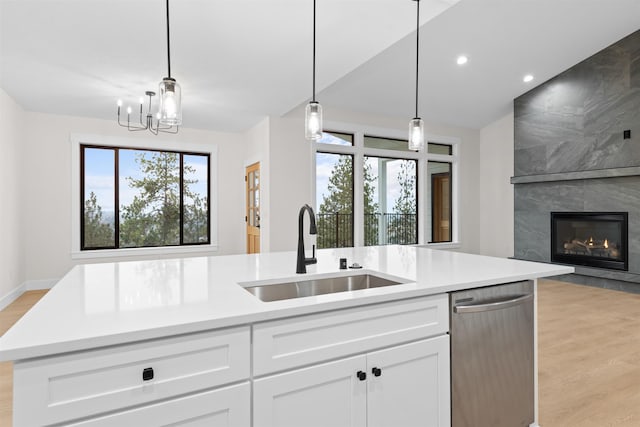 kitchen with dishwasher, a sink, light countertops, open floor plan, and light wood-style flooring