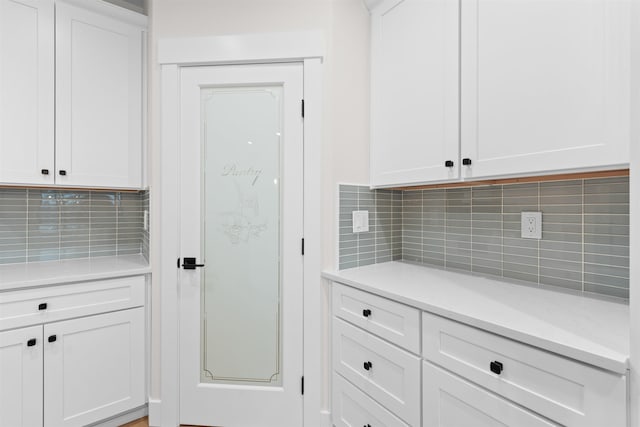 kitchen with light countertops, tasteful backsplash, and white cabinets