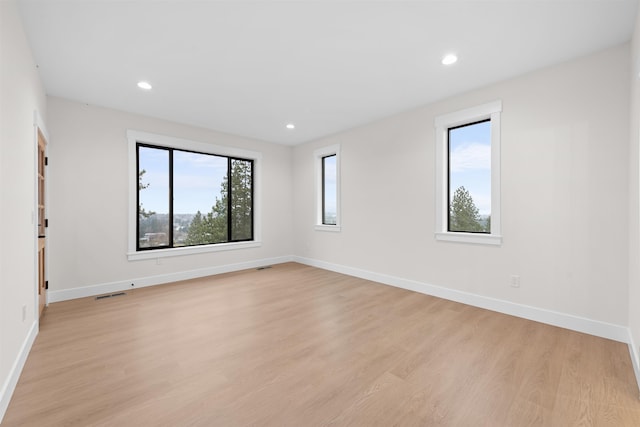 spare room with light wood-type flooring, recessed lighting, baseboards, and visible vents