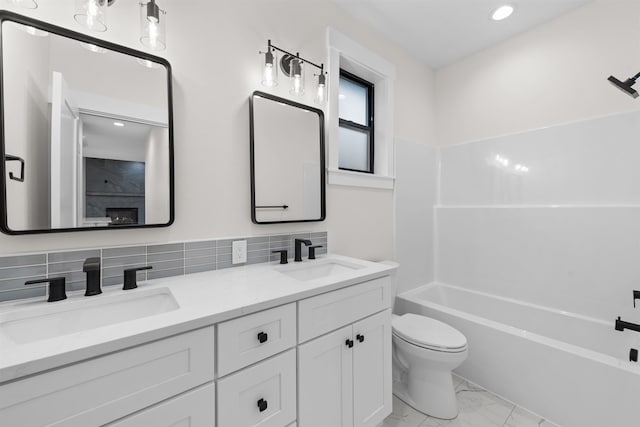 bathroom with double vanity, a sink, marble finish floor, and toilet