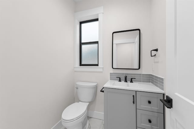half bath featuring toilet, baseboards, marble finish floor, and vanity