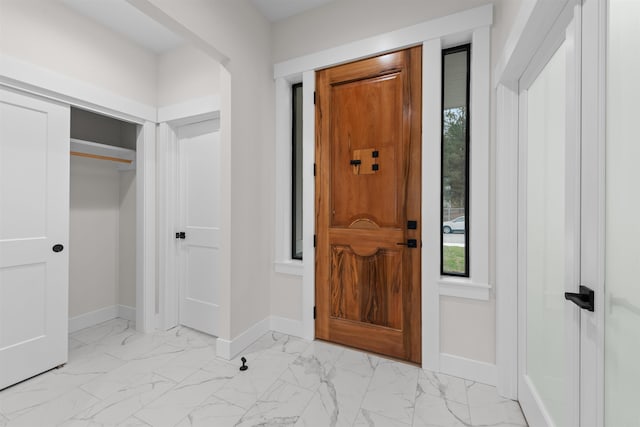 entrance foyer featuring baseboards, a wealth of natural light, and marble finish floor