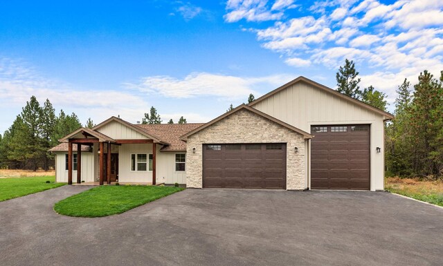 ranch-style house with board and batten siding, a garage, a front lawn, and aphalt driveway