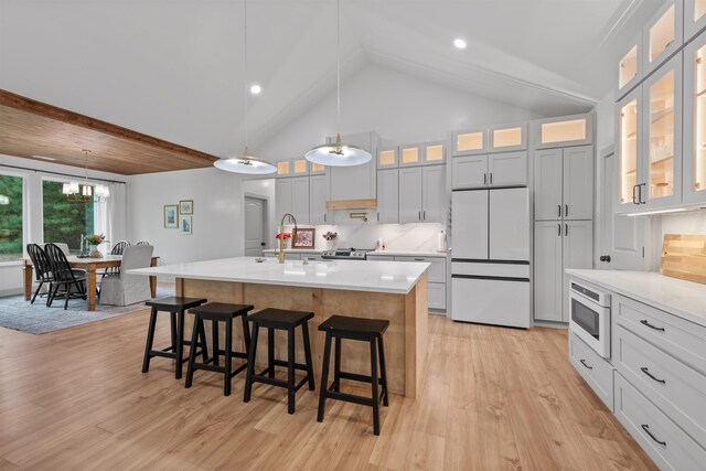 kitchen featuring a sink, light countertops, a breakfast bar area, and white appliances