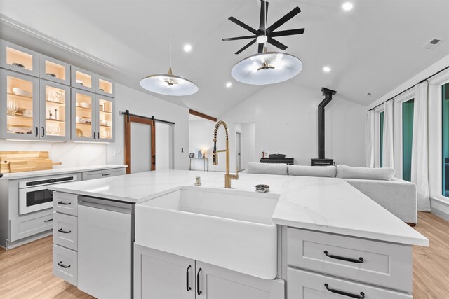 kitchen with visible vents, a barn door, dishwasher, a sink, and open floor plan
