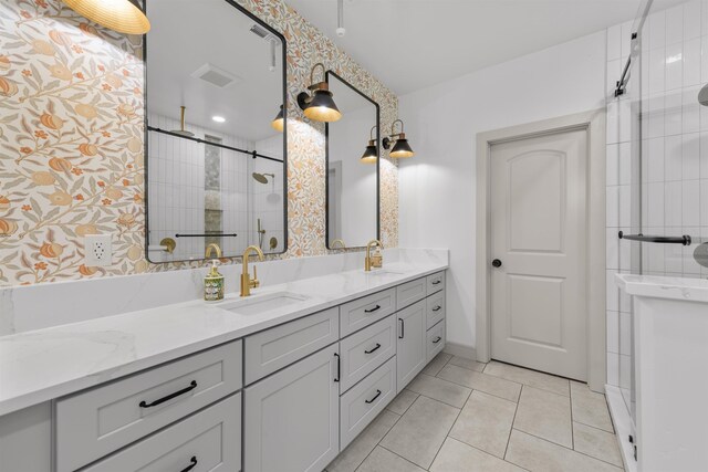 full bathroom with double vanity, a sink, a stall shower, and tile patterned floors