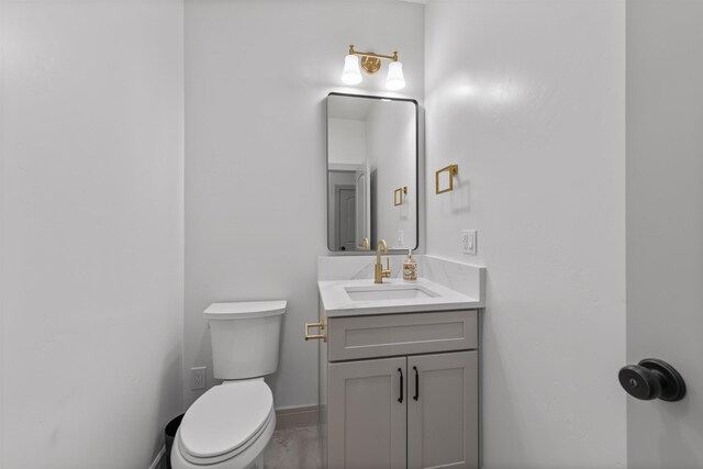 half bath featuring vanity, baseboards, and toilet