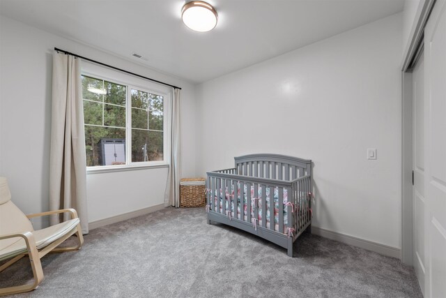 bedroom featuring a nursery area, carpet, baseboards, visible vents, and a closet
