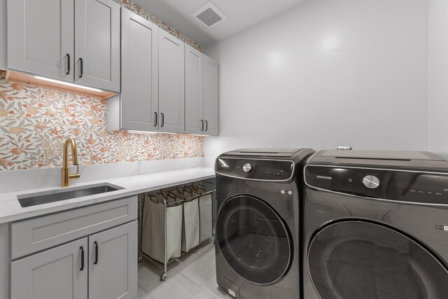 washroom featuring visible vents, cabinet space, a sink, light tile patterned floors, and separate washer and dryer
