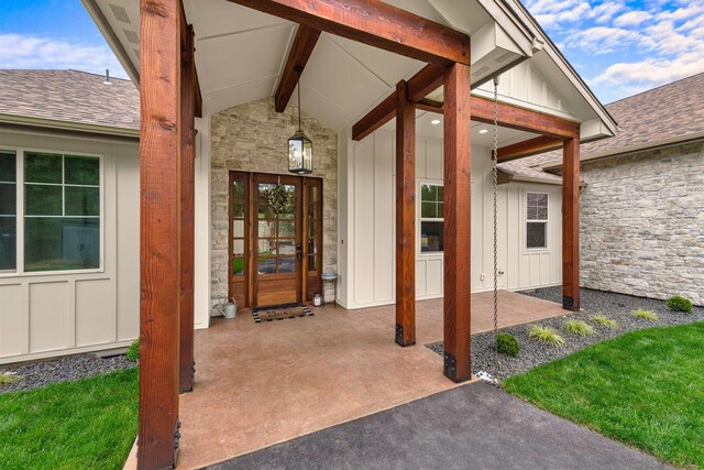 doorway to property with a shingled roof, board and batten siding, and stone siding