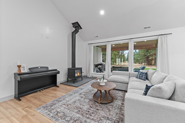 living area with visible vents, a wood stove, light wood-style flooring, and baseboards