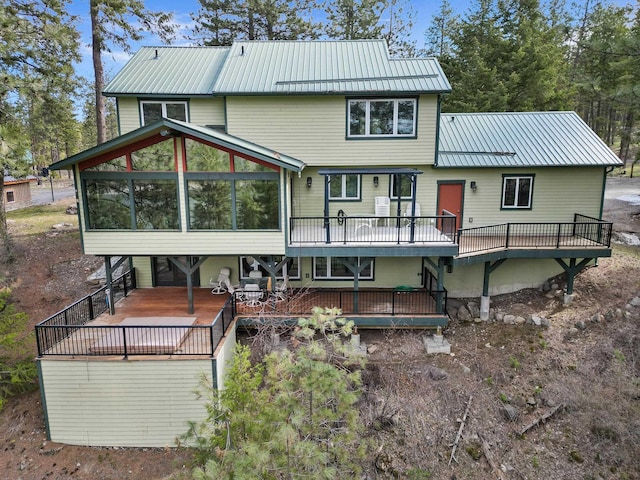 rear view of property with a sunroom, a deck, and metal roof