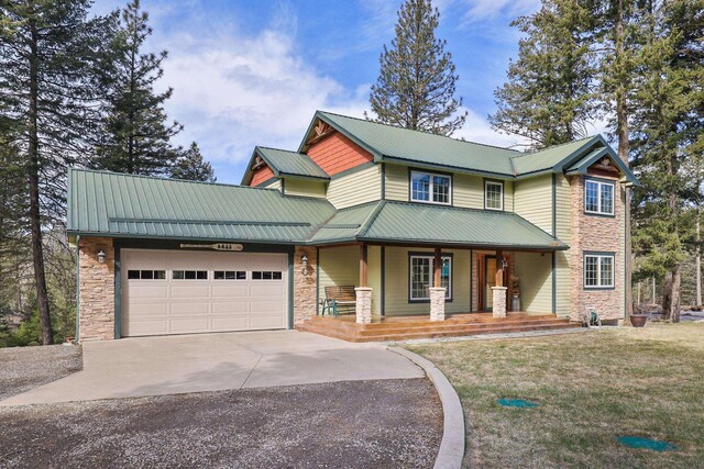 view of front of home featuring an attached garage, stone siding, covered porch, driveway, and metal roof