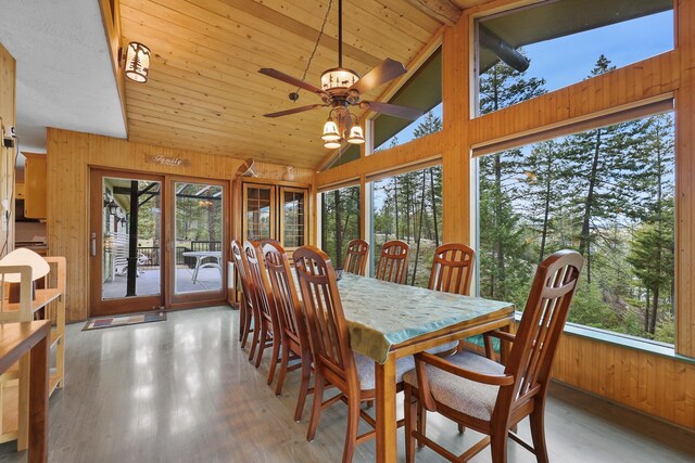 dining space featuring a ceiling fan, wood finished floors, wooden walls, and a healthy amount of sunlight