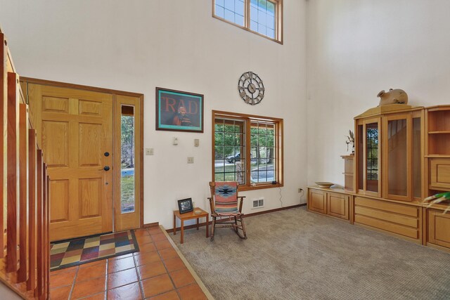 tiled foyer entrance with visible vents, a towering ceiling, and a healthy amount of sunlight