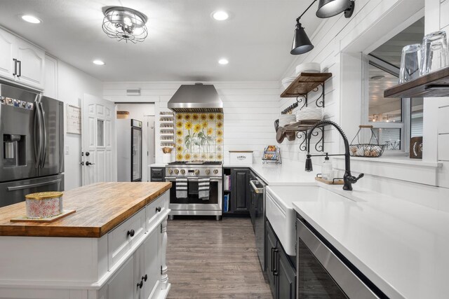 kitchen featuring exhaust hood, appliances with stainless steel finishes, open shelves, white cabinets, and wood counters