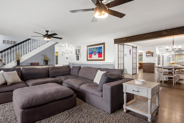 living room featuring stairway, visible vents, wood finished floors, and ceiling fan with notable chandelier
