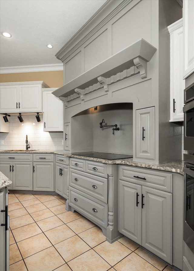 22828 S Gateway Ln, Cheney, WA 99004 - kitchen featuring decorative backsplash, crown molding, black electric cooktop, light tile patterned floors, and white cabinetry