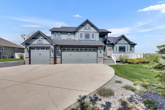 craftsman house with stone siding, a garage, a front yard, concrete driveway, and covered porch