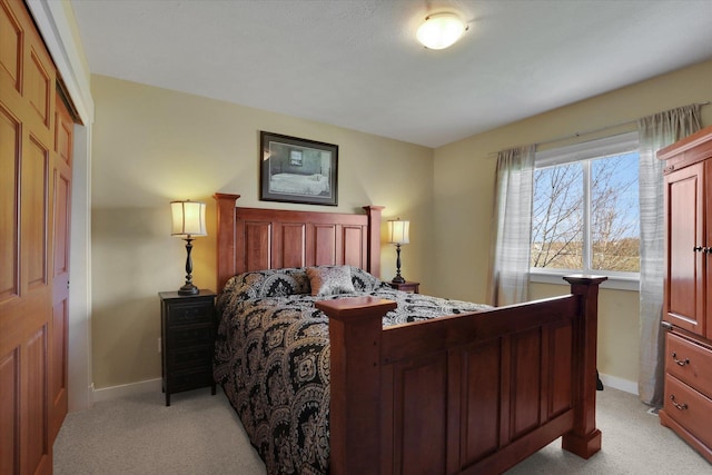 bedroom with baseboards, a closet, and light carpet