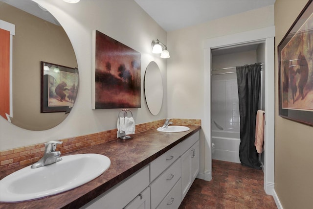 bathroom with double vanity, a sink, stone finish flooring, and baseboards