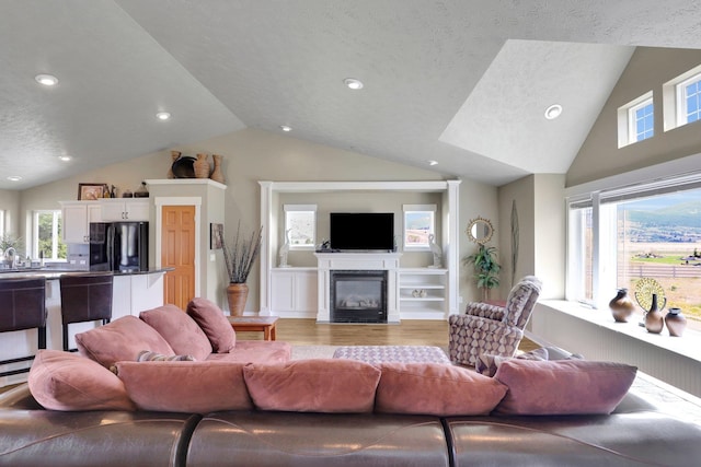 19121 E 21st Ct, Greenacres, WA 99016 - living room with light wood-style flooring, a glass covered fireplace, recessed lighting, plenty of natural light, and a textured ceiling