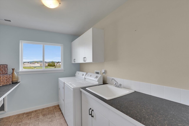 laundry area featuring washer and dryer, cabinet space, a sink, baseboards, and visible vents