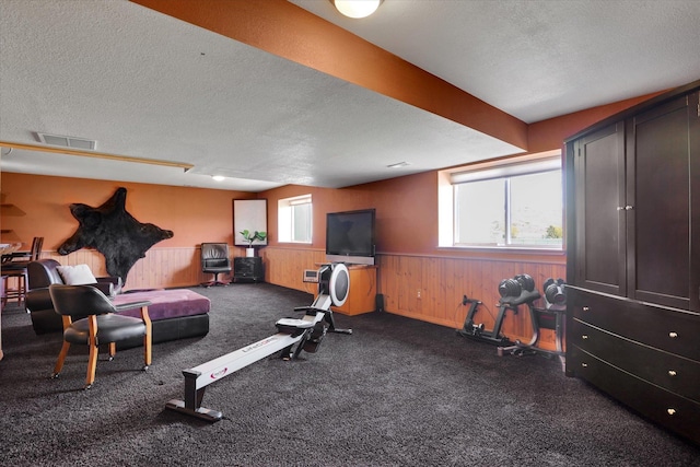 workout room featuring visible vents, a textured ceiling, a wainscoted wall, and wooden walls