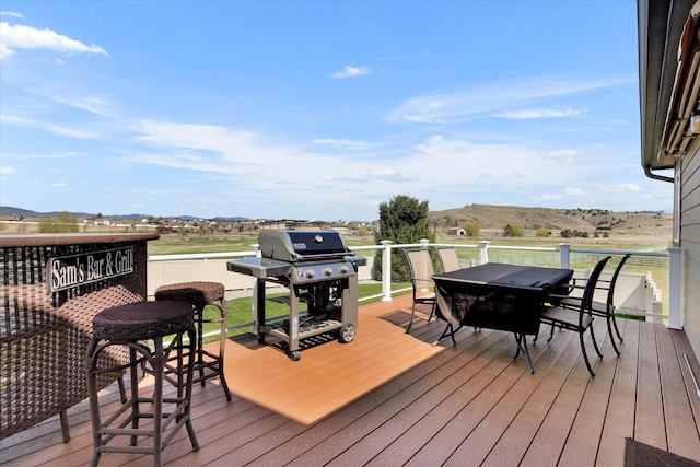 deck featuring outdoor dining space, a mountain view, and area for grilling