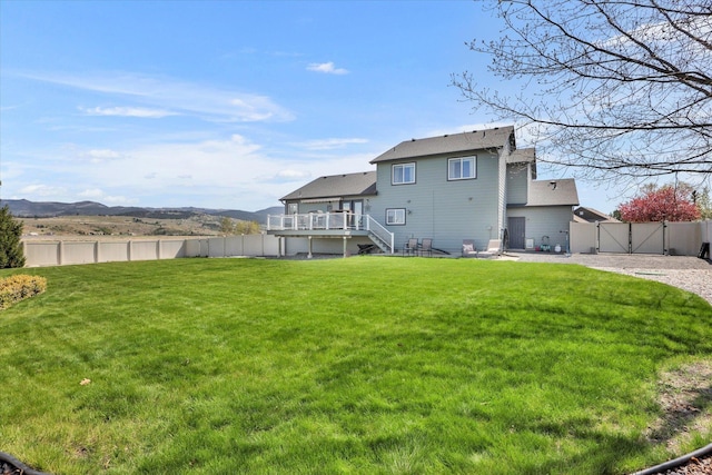 rear view of property with a deck with mountain view, a gate, a fenced backyard, and stairs