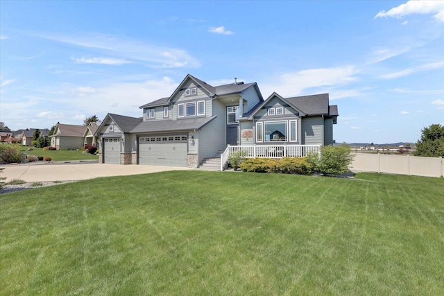 craftsman-style home featuring concrete driveway, fence, covered porch, and a front yard