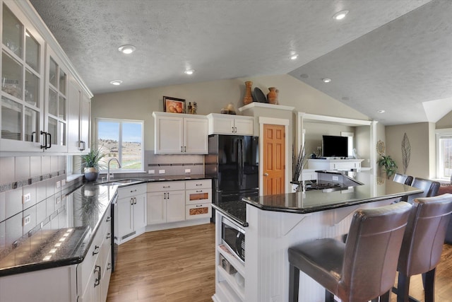 kitchen with a sink, a textured ceiling, open floor plan, tasteful backsplash, and vaulted ceiling