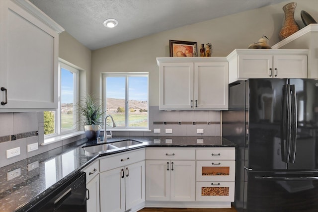kitchen featuring a sink, black appliances, vaulted ceiling, and tasteful backsplash
