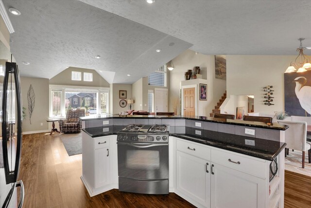 kitchen featuring dark wood-style flooring, range with gas stovetop, white cabinetry, open floor plan, and vaulted ceiling